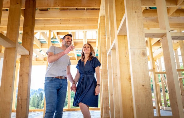 A man and woman stand inside of a home being built.