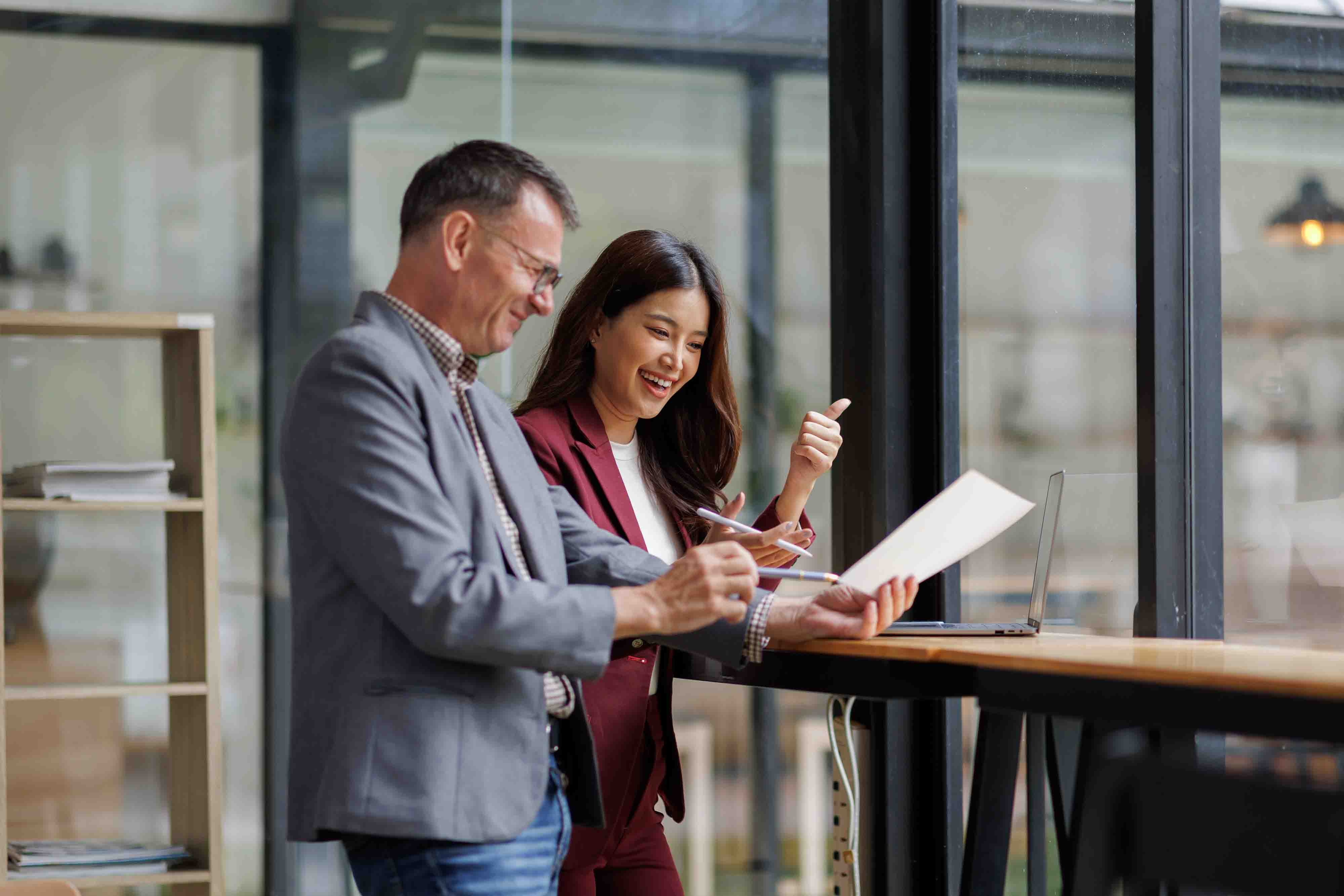 A man and a woman stand together and look at a computer.