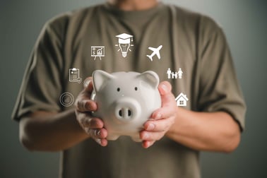 A person holds a piggy bank surrounded by icons of financial symbols.