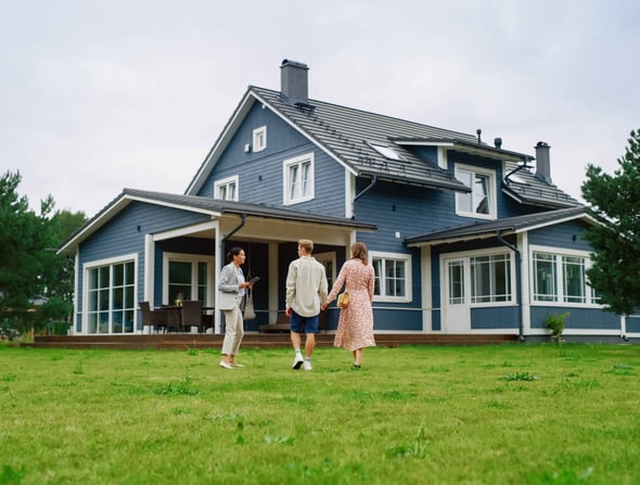 A man and woman stand in front of a home with a realtor.