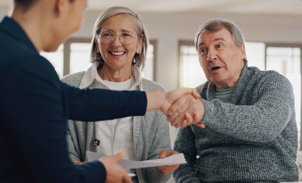 A man and woman shake hands with a financial advisor.