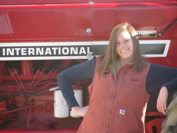 Jennifer Keister stands in front of an International Harvestor Tractor