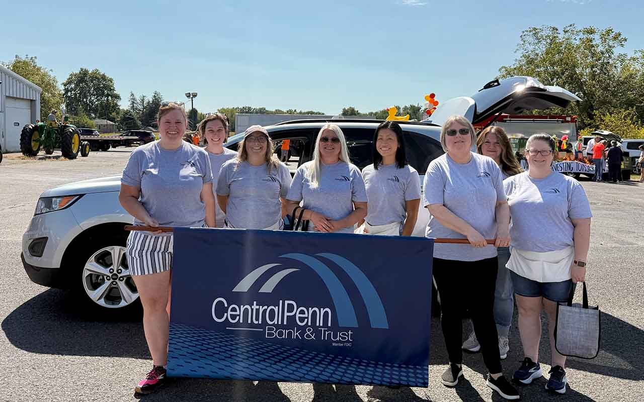 Central Penn employees hold a bank banner before a parade.