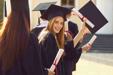 A female graduate holds up a diploma.