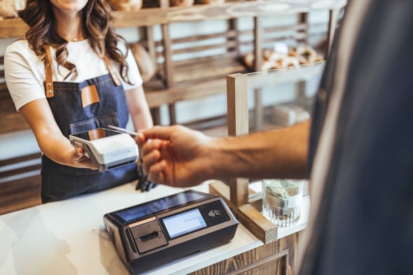 A person uses tap to pay with a credit card in a shop.
