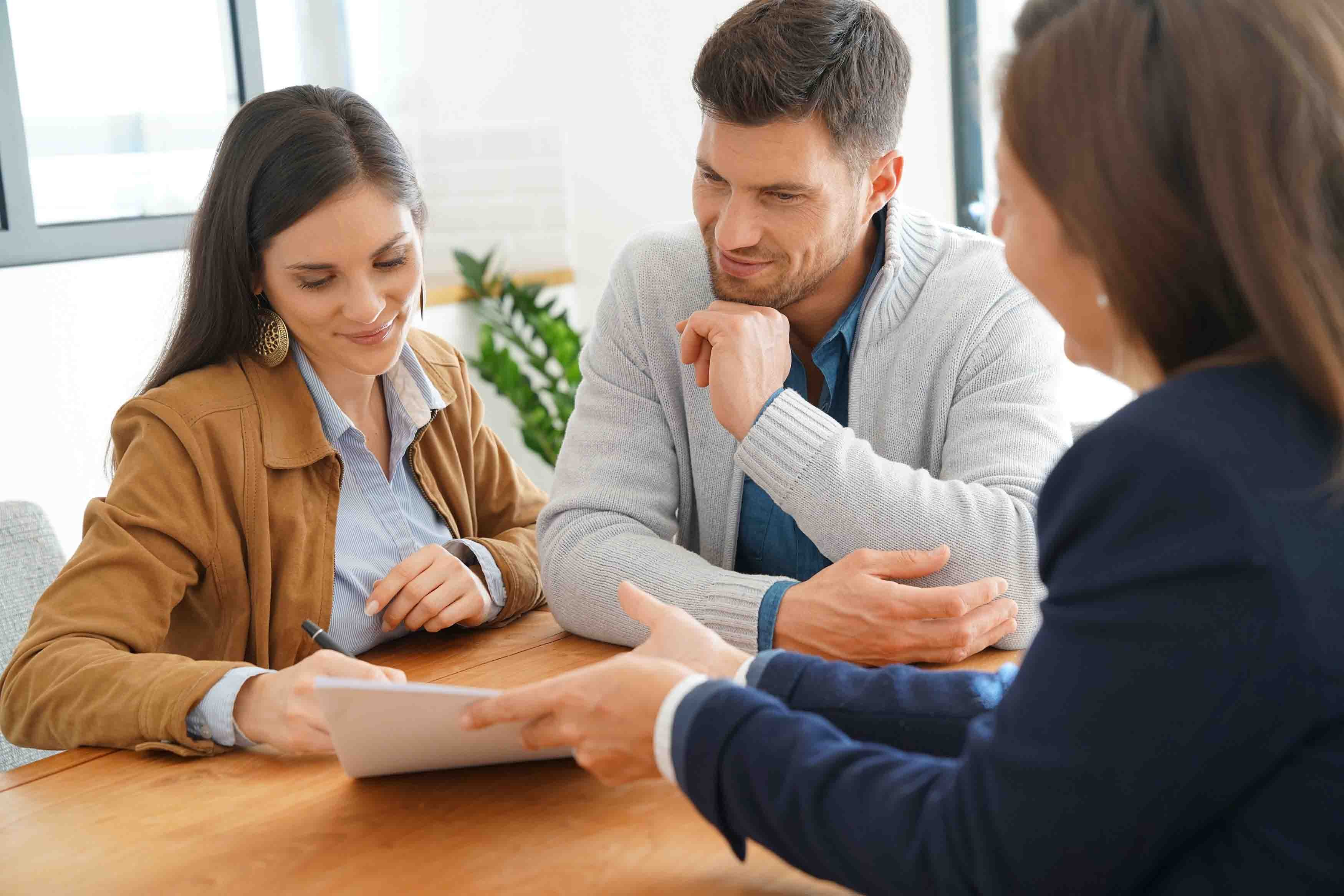 A couple sits with a financial advisor and reviews documents.