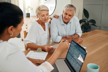 A man and woman sit at kitchen table around a computer with female advisor.