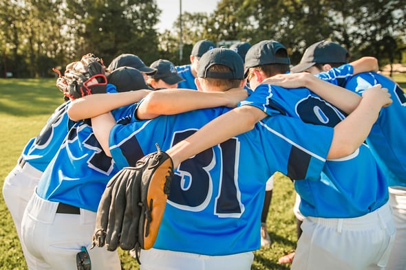 Team of youth baseball players in a team huddle.